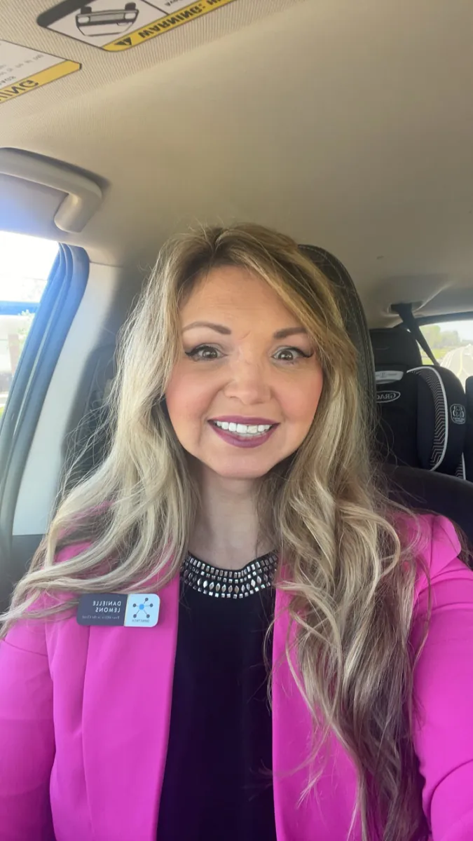 Danielle Lemons in a pink blazer. Danielle Lemons, Vice President of Operations at DirecTech Connect, smiling in a pink blazer with her name badge.
